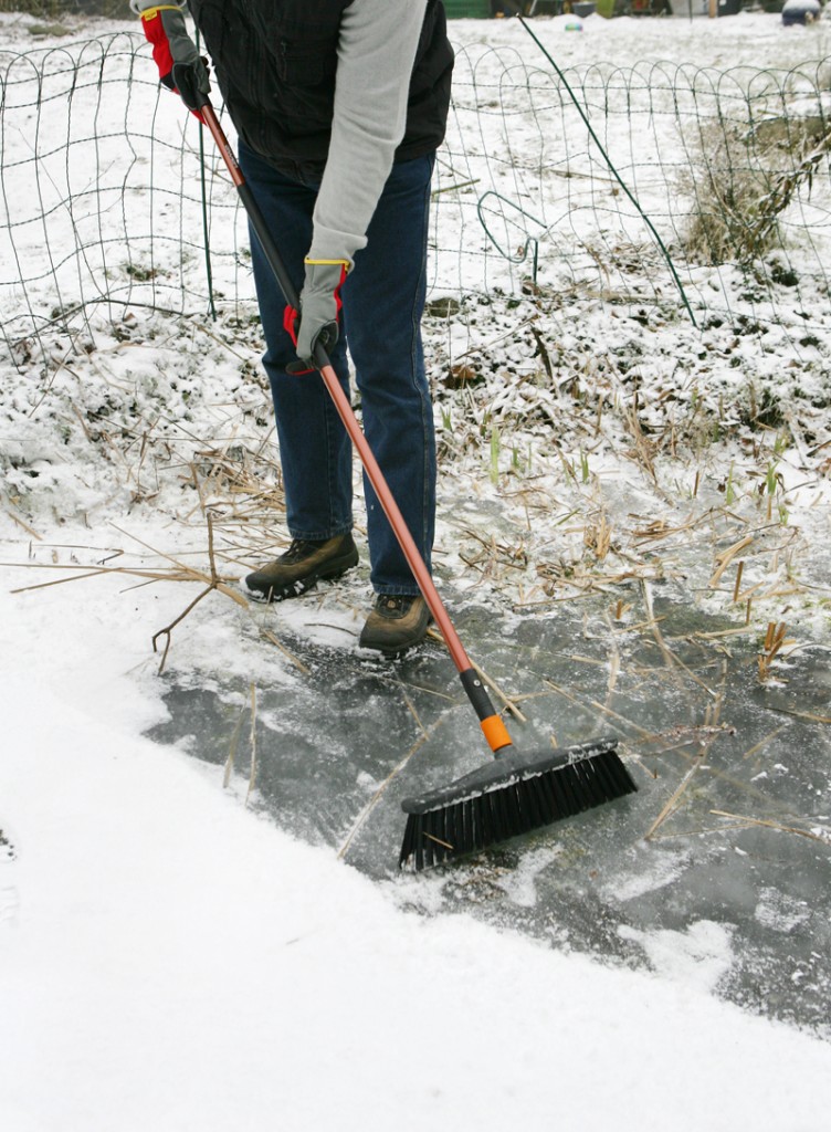 Eine geschlossene Schneedeck abfegen, um die Pflanzen mit Licht zu versorgen